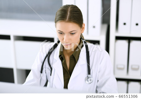 Doctor typing on pc computer while sitting at the desk in hospital office. Physician woman at work. Data in medicine and healthcare 66551306