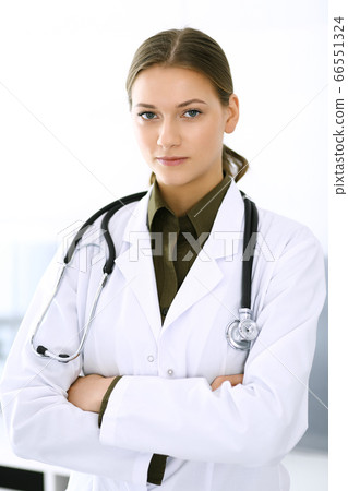 Doctor woman standing straight and looking at camera. Perfect medical service in clinic. Happy future in medicine and healthcare Doctor woman standing straight and looking at camera. Perfect medical service in clinic. Happy future in medicine and healthcare 66551324