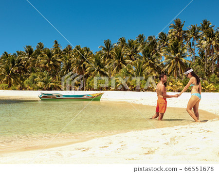 Lovely couple relaxing at the white sandy beach with palm trees in Onok Island in Balabac Palawan Lovely couple relaxing at the white sandy beach with palm trees in Onok Island in Balabac Palawan 66551678