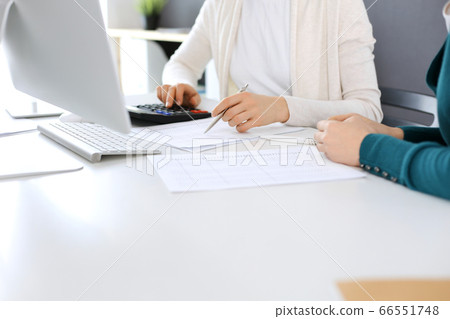 Accountant checking financial statement or counting by calculator income for tax form, hands close-up. Business woman sitting and working with colleague at the desk in office. Audit concept Accountant checking financial statement or counting by calculator income for tax form, hands close-up. Business woman sitting and working with colleague at the desk in office. Audit concept 66551748