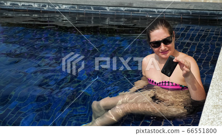 disappointed lady takes out smartphone from pool water 66551800