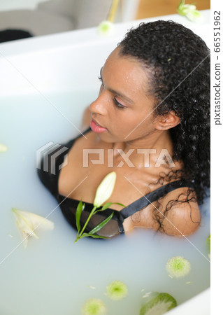 Portrait of black girl taking milk bath and wearing swimsuit. Portrait of black girl taking milk bath and wearing swimsuit. 66551962