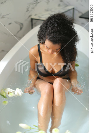 Balck curly haired girl in underwear taking bath with flowers. 66552006