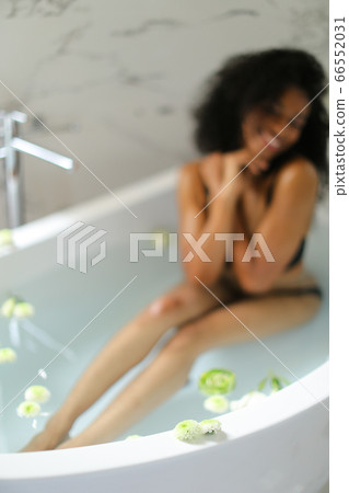 Focus on flower, black smiling girl taking bath and wearing underwear. 66552031