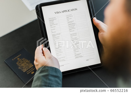 Close up businessman getting visa and reading application on tablet, passport on desk. Close up businessman getting visa and reading application on tablet, passport on desk. 66552216