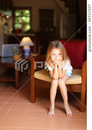 Little girl sitting in wooden chair in living room. 66552507