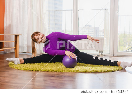 Positive lady exercise splits with ball indoors Positive lady exercise splits with ball indoors 66553295