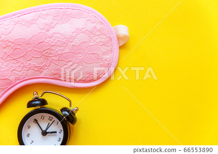 Sleeping mask and alarm clock on yellow background Sleeping mask and alarm clock on yellow background 66553890