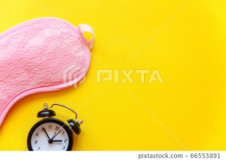 Sleeping mask and alarm clock on yellow background 66553891