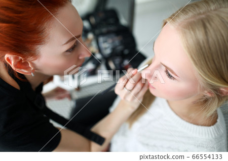 Makeup artist does makeup face to blonde girl Makeup artist does makeup face to blonde girl 66554133