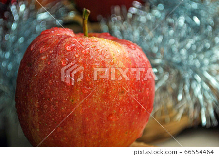 A single red apple with water drops on it in festive background 66554464