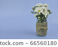 White daisy bouquet of  flowers in jar decor with sack on blue background. 66560180