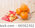 Chinese New Year - Mandarin orange, gold sycee (Foreign text means wealth) and red packet (Foreign text means spring season) on white painted wood table 66562302
