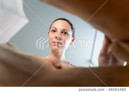 Caucasian woman peeking into craft paper delivery package with happy emotion. 66563480