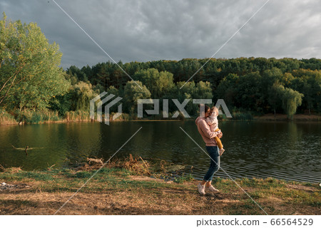 Mother and baby girl sitting near lake. Local travel. New normal vacation. Mother's day Mother and baby girl sitting near lake. Local travel. New normal vacation. Mother's day 66564529