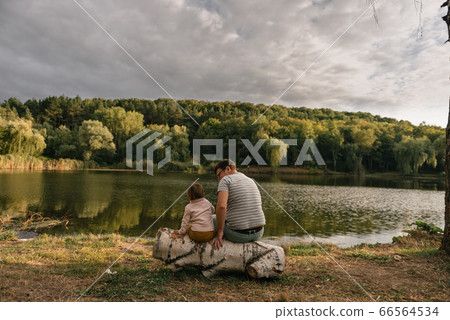 Father and baby girl sitting near lake. Local travel. New normal vacation. Father's day Father and baby girl sitting near lake. Local travel. New normal vacation. Father's day 66564534