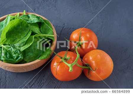 Fresh spinach leaves in wooden bowl and tomato on 66564899
