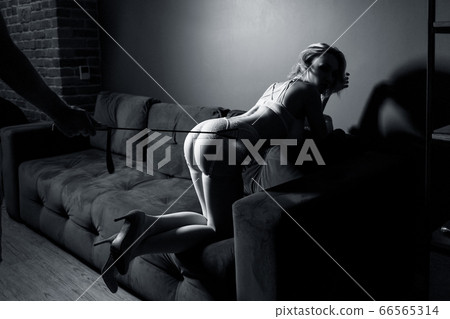 Submissive woman slave waiting. Leather whip over her buttocks. 66565314