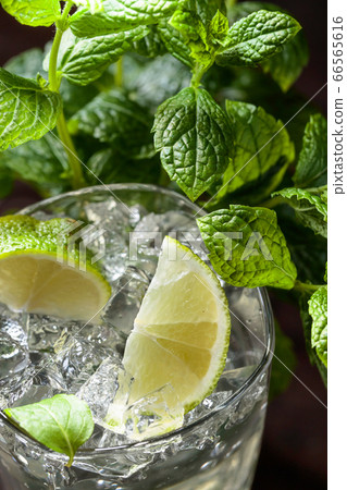 Glass with ice, mint leaves and lime slices. 66565616