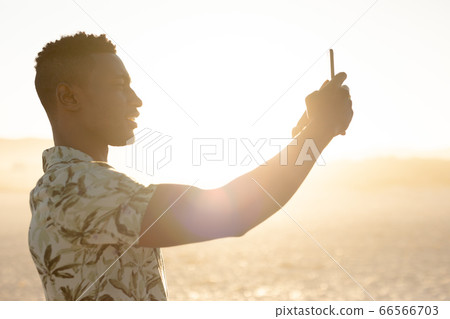 African Amercian man taking pictures on the beach African Amercian man taking pictures on the beach 66566703