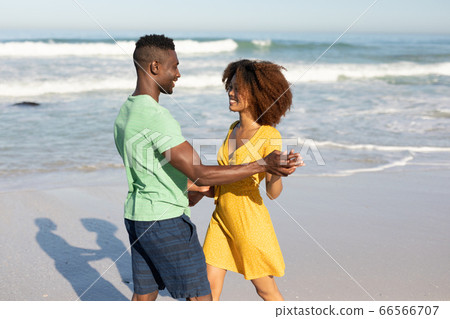 Mixed race couple dancing on the beach Mixed race couple dancing on the beach 66566707