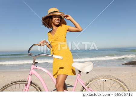 Mixed race woman with a bike on the beach 66566712
