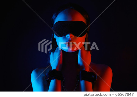 Girl in handcuffs and mask. in color lights. tied hands and