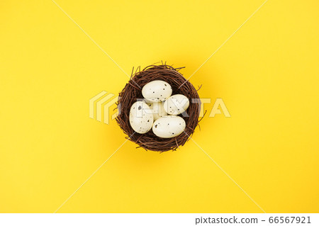 Nest with eggs on bright yellow background. Easter concept. Flat lay, top view, copy space Nest with eggs on bright yellow background. Easter concept. Flat lay, top view, copy space 66567921