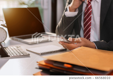 Male businessman using digital tablet analyzes business data, busy working on laptop computer with tablet and business report on office desk, business strategy analysis concept. 66568010