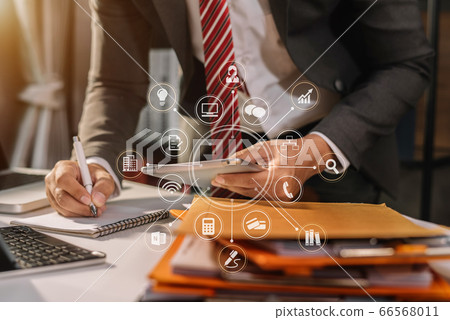 Male businessman or Designer using tablet with laptop and document on desk in modern office with virtual interface graphic icons network diagram. Male businessman or Designer using tablet with laptop and document on desk in modern office with virtual interface graphic icons network diagram. 66568011