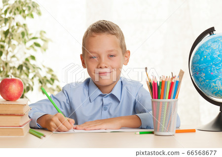 Young schoolboy sitting at the table and doing Young schoolboy sitting at the table and doing 66568677