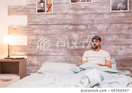 Tired man wearing a sleep mask Tired man wearing a sleep mask 66568947
