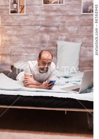 Man laying in bed in wearing pajamas 66568948