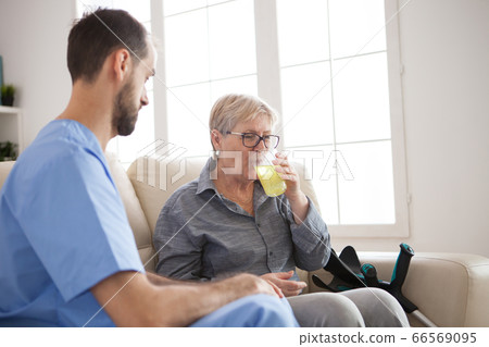 Young caregiver sitting down on couch with senior woman Young caregiver sitting down on couch with senior woman 66569095