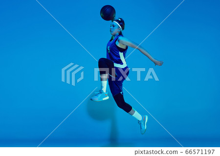 Young caucasian female basketball player isolated on blue studio background in neon light 66571197