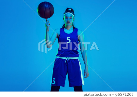 Young caucasian female basketball player isolated on blue studio background in neon light Young caucasian female basketball player isolated on blue studio background in neon light 66571205