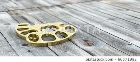 Brass knuckle-duster, weapon for hand on wooden table 3d render illustration 66571982