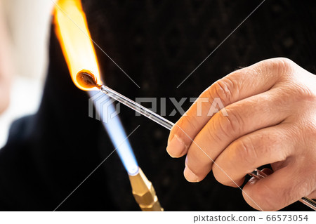 Glassblower man shaping the glass Glassblower man shaping the glass 66573054