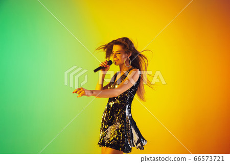 Caucasian female singer portrait isolated on gradient studio background in neon light 66573721