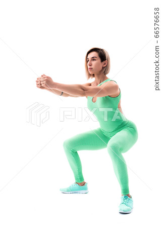 Studio shot of an athletic woman doing squats isolated over white background Studio shot of an athletic woman doing squats isolated over white background 66576658