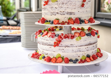 beautiful delicious Wedding cake in many tiers with fresh wild berries and fruits beautiful delicious Wedding cake in many tiers with fresh wild berries and fruits 66577152