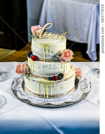 Beautiful wedding cake with cream With text Love on top pink flowers roses Beautiful wedding cake with cream With text Love on top pink flowers roses 66577659
