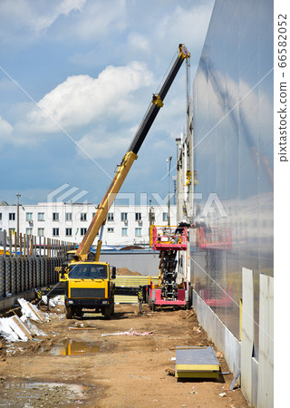 Builders work at a construction site with a cradle Builders work at a construction site with a cradle 66582052