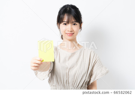 Young woman showing a yellow card 66582062