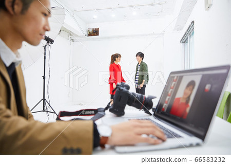 Young female model in red coat and photographer 66583232