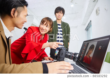 Young female model in red coat and photographer 66583292
