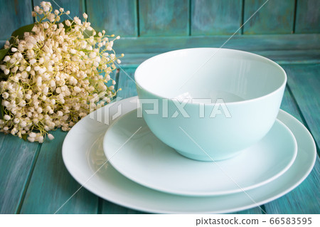 Vintage table setting with bouquet of lilies of the valley, empty dishes in teal color Vintage table setting with bouquet of lilies of the valley, empty dishes in teal color 66583595