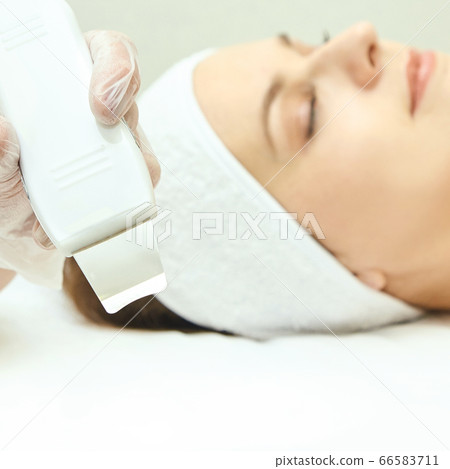 Ultrasonic skin equipment. Woman face cosmetology treatment. Girl clinic facial Ultrasonic skin equipment. Woman face cosmetology treatment. Girl clinic facial 66583711