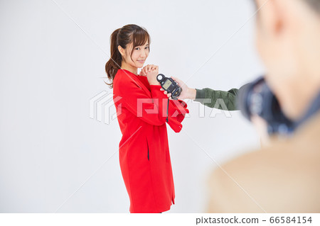Young female model in red coat and photographer Young female model in red coat and photographer 66584154