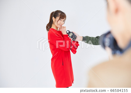 Young female model in red coat and photographer Young female model in red coat and photographer 66584155